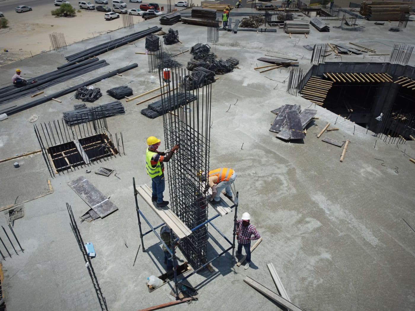 Concrete columns rising from a finished slab with workers on site